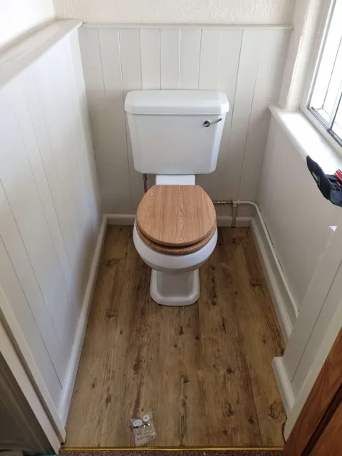 Toilet and cistern in a panelled cloakroom.