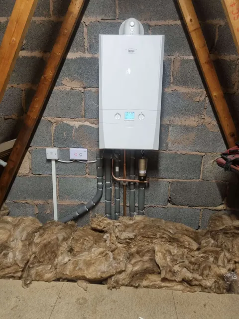 Boiler and connected pipework beneath exposed roof timbers.