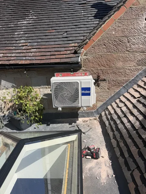 Haier outdoor air-conditioning unit mounted on a wall above a roof.