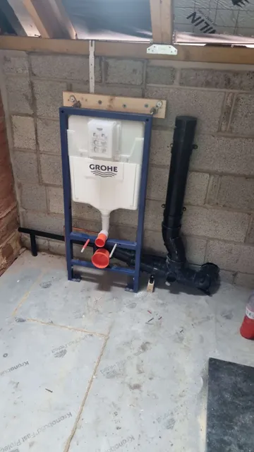 Concealed toilet cistern and frame in an unfinished room.