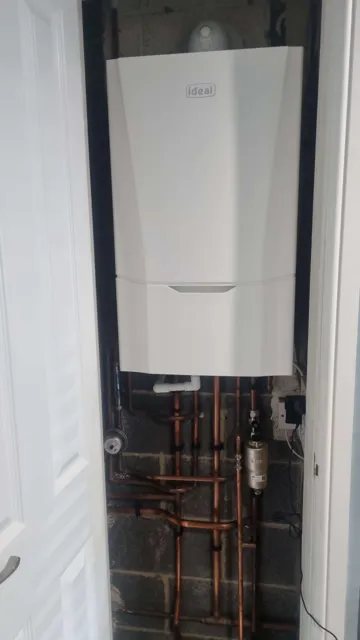 Boiler and copper pipework within a cupboard recess.