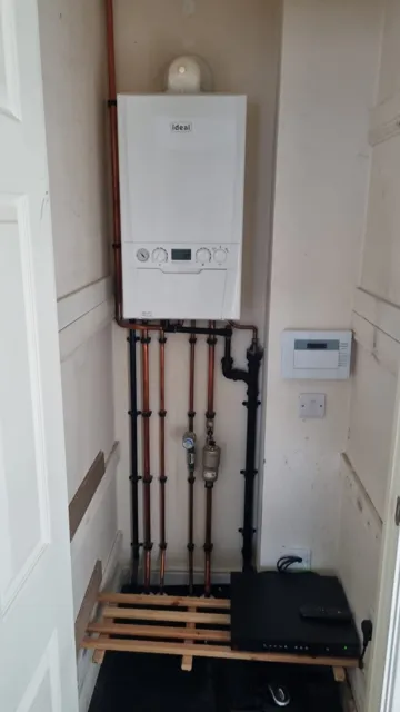 Wall-mounted boiler with visible pipe connections and controls.