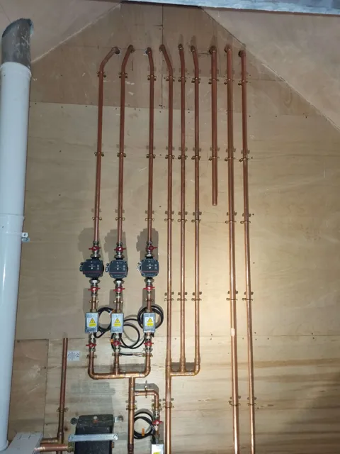 Copper pipe runs and heating controls on an exposed wall.