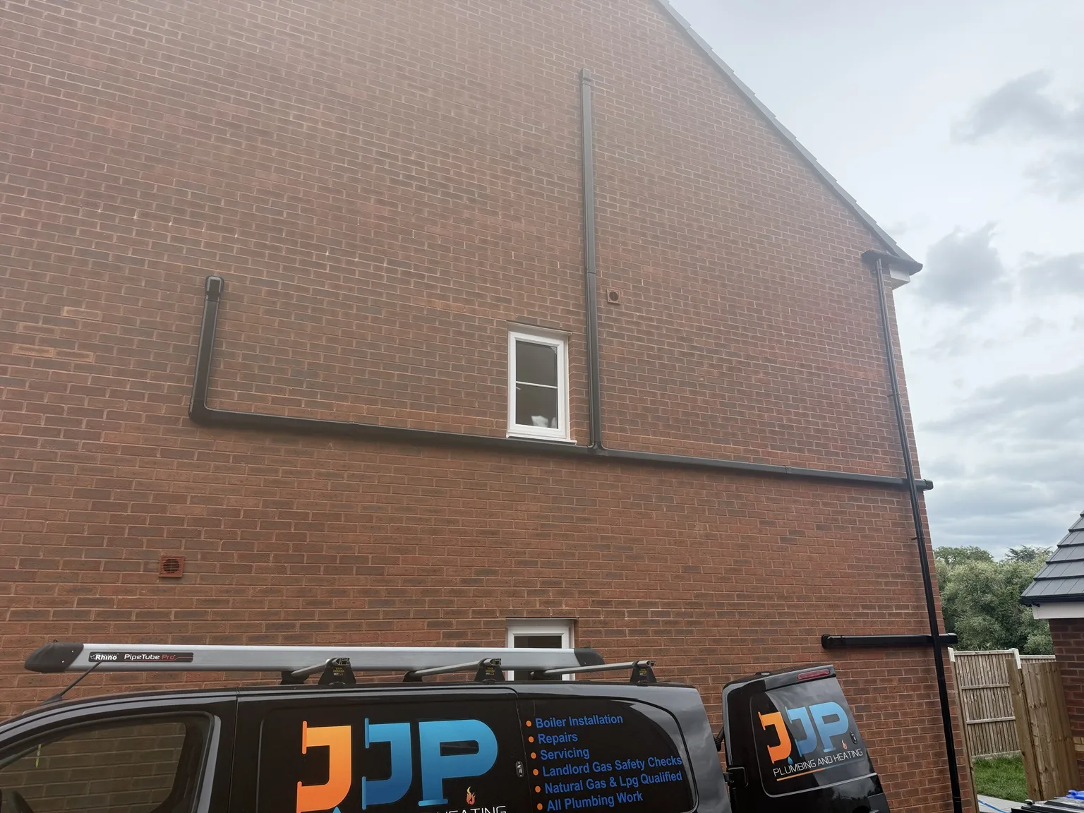JJP Plumbing & Heating branded van parked outside a brick house.